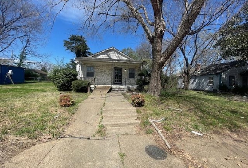 Bungalow-style house featuring stone siding, a front yard, and covered porch