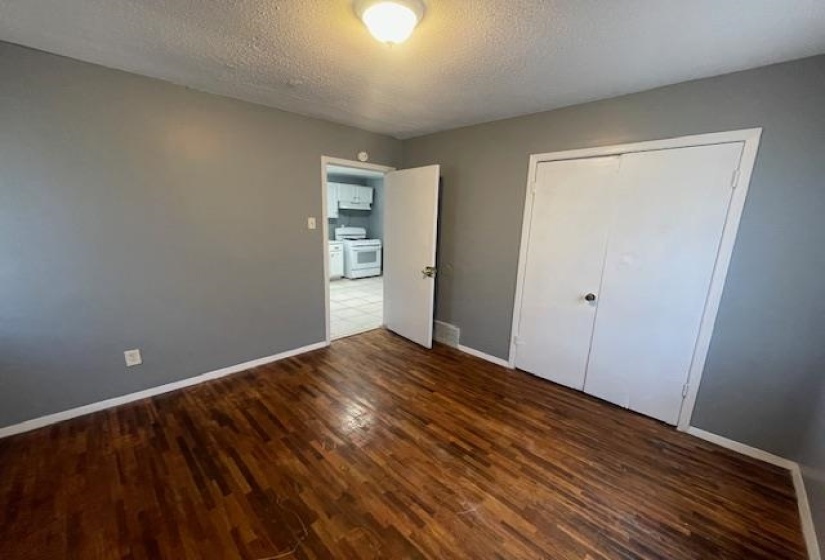 Unfurnished bedroom featuring baseboards, a closet, wood finished floors, and a textured ceiling