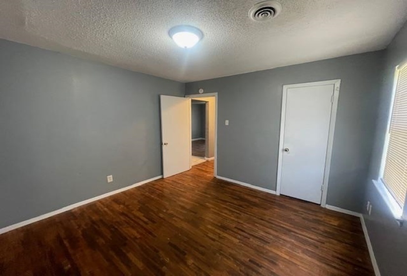 Unfurnished bedroom with baseboards, visible vents, and wood finished floors