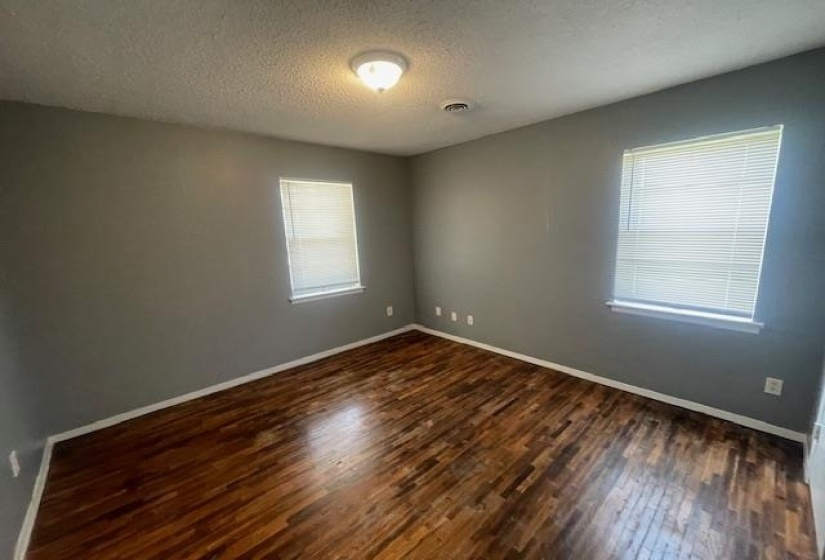 Unfurnished room featuring dark wood-style floors, visible vents, baseboards, and a textured ceiling