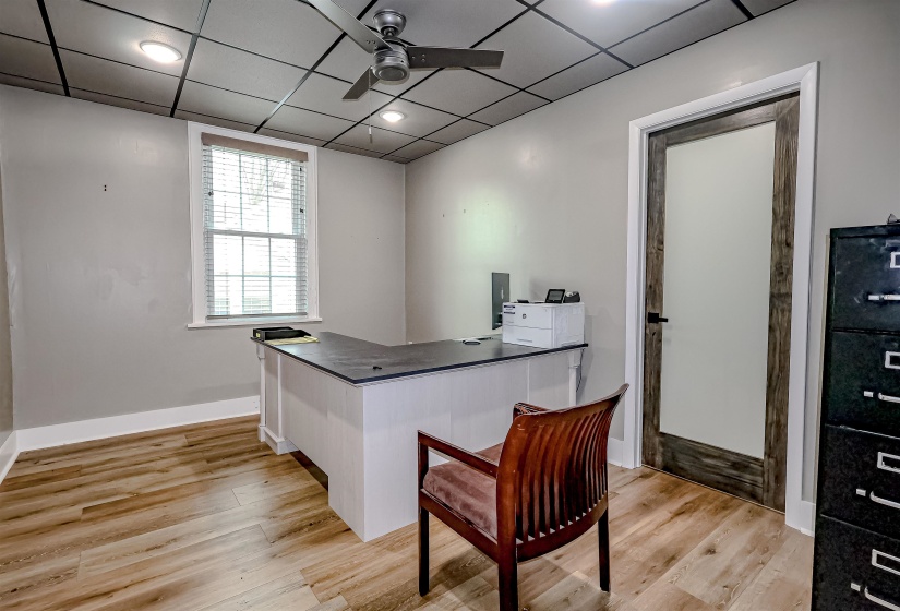 Office space featuring baseboards, light wood-style flooring, a drop ceiling, and a ceiling fan