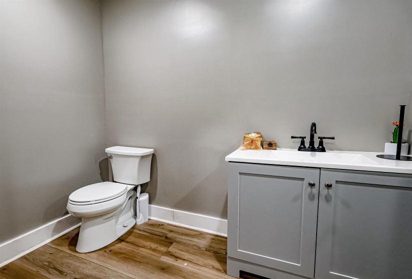 Half bathroom featuring toilet, baseboards, and wood finished floors
