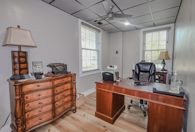 Home office featuring baseboards, wood finished floors, ceiling fan, and a drop ceiling