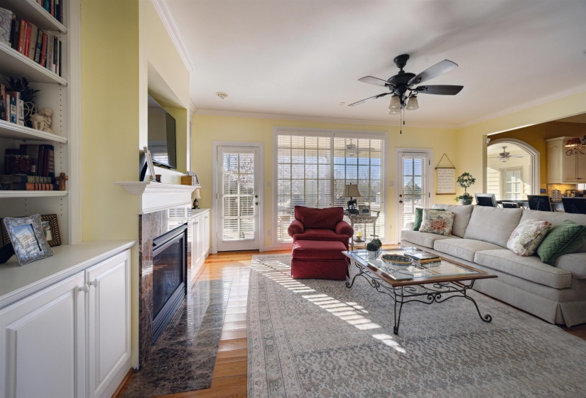 Living room with light wood-type flooring, a premium fireplace, ornamental molding, and a ceiling fan