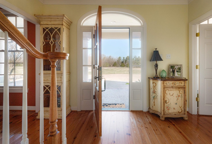 Foyer with baseboards, light wood-type flooring, ornamental molding, and a healthy amount of sunlight
