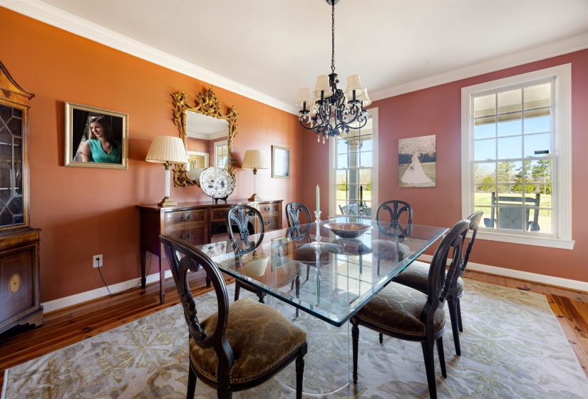 Dining room with a notable chandelier, crown molding, baseboards, and wood finished floors