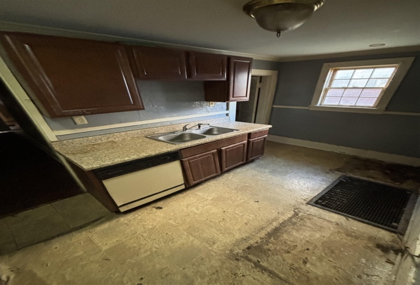 Kitchen featuring light countertops, ornamental molding, baseboards, a sink, and dishwasher