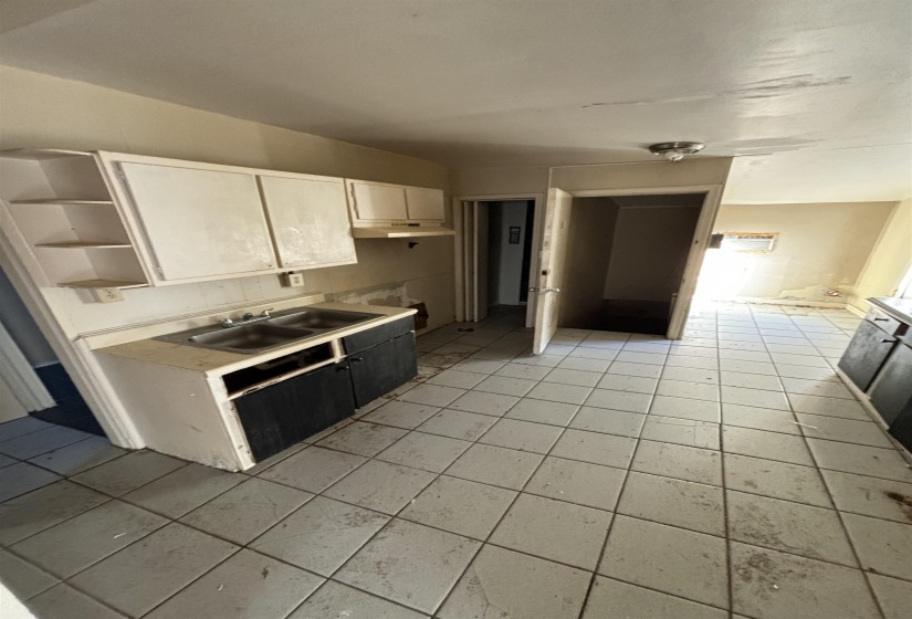 Kitchen with white cabinetry, light countertops, a sink, and light tile patterned floors