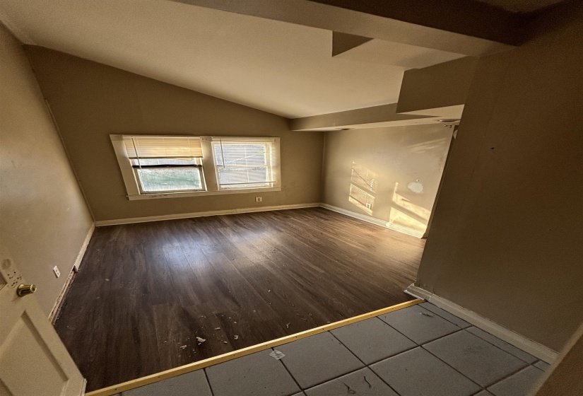 Empty room featuring baseboards, vaulted ceiling, and wood finished floors