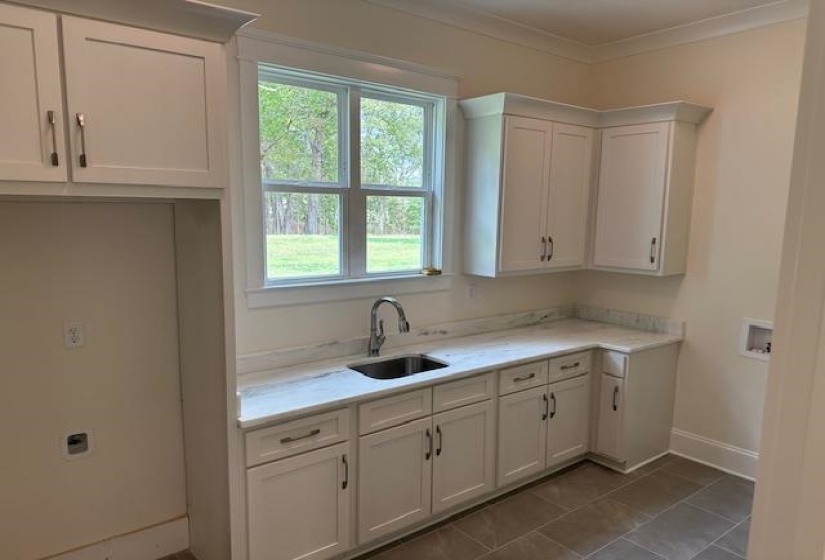 Kitchen featuring light stone counters, sink, white cabinets, and ornamental molding