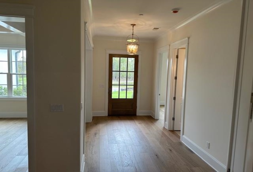 Entryway with light hardwood / wood-style floors, crown molding, and an inviting chandelier