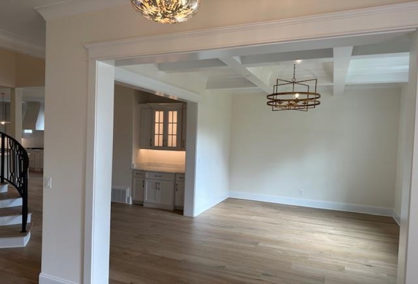 Unfurnished dining area featuring hardwood / wood-style floors, coffered ceiling, beamed ceiling, and an inviting chandelier