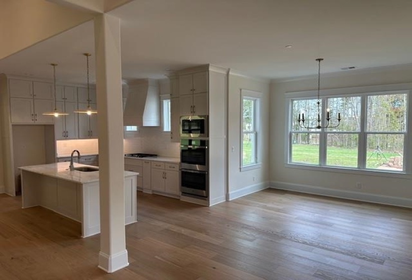 Kitchen with a kitchen island with sink, sink, and light wood-type flooring