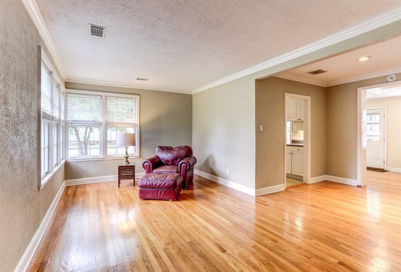 Sitting room with crown molding, light wood-style floors, a textured wall, and a textured ceiling