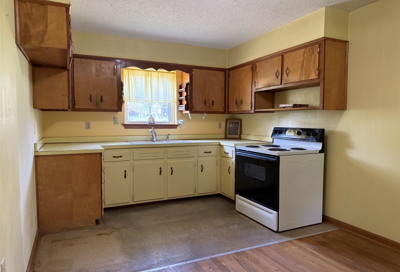 Kitchen featuring a sink, a textured ceiling, electric range oven, and open shelves