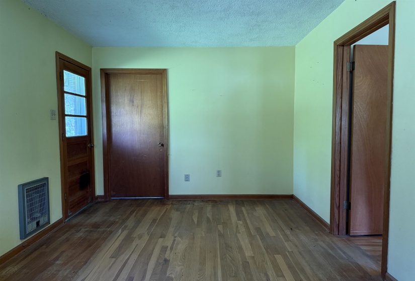 Interior space featuring baseboards, a textured ceiling, heating unit, a closet, and wood finished floors