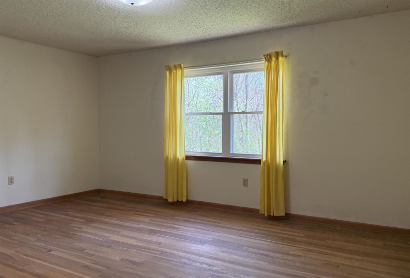 Spare room featuring baseboards, a textured ceiling, and wood finished floors