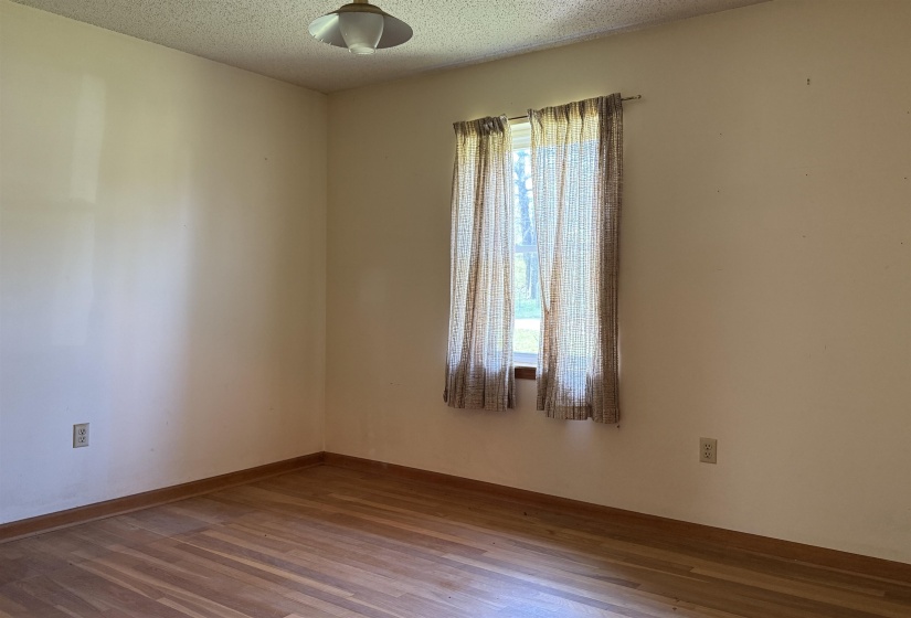 Unfurnished room featuring baseboards, a textured ceiling, and wood finished floors