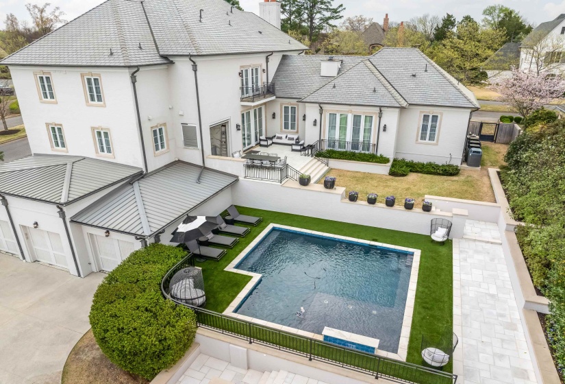 Back of property featuring an outdoor pool, a chimney, a fenced backyard, stucco siding, and a yard
