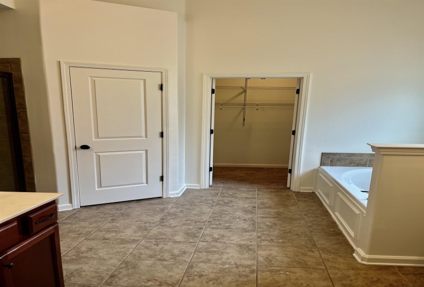 Bathroom with tile patterned flooring, baseboards, a walk in closet, and a bath. Separate tub and shower