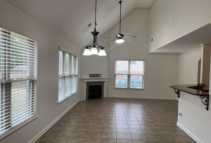 Unfurnished living room with visible vents, baseboards, a fireplace, a ceiling fan, and tile patterned flooring