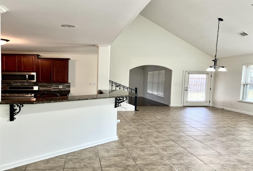 Kitchen with visible vents, appliances with stainless steel finishes, arched walkways, dark stone countertops, and backsplash