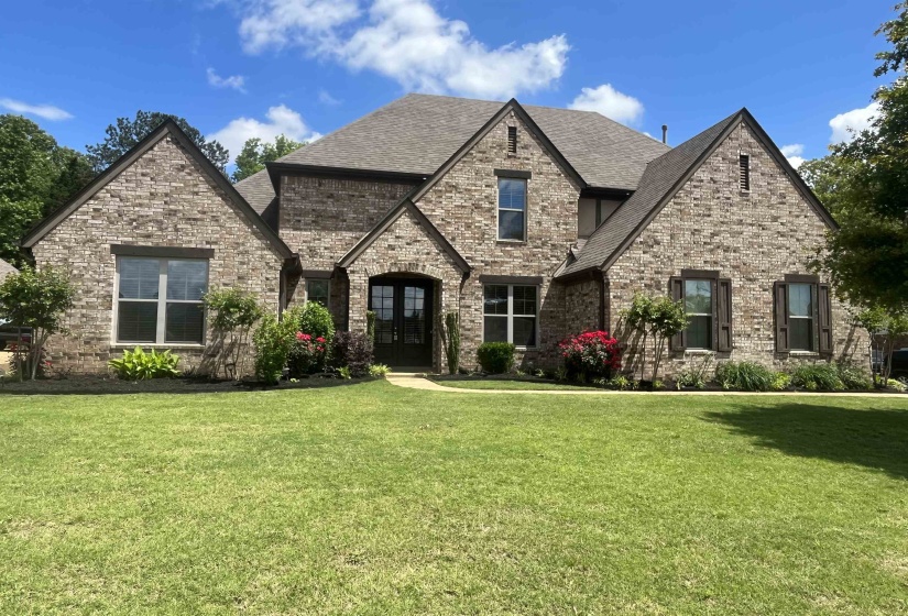 French country style house featuring brick siding, roof with shingles, french doors, and a front yard