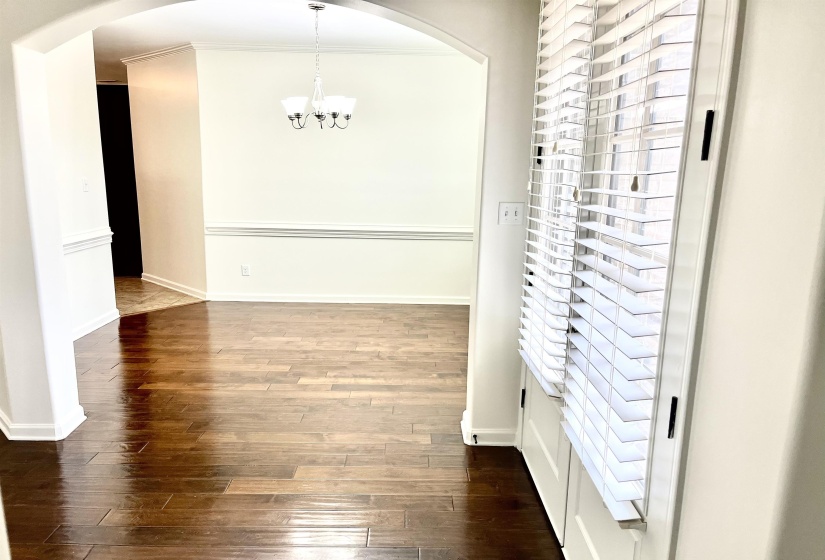 Interior space featuring dark wood-style floors, a notable chandelier, arched walkways, and baseboards