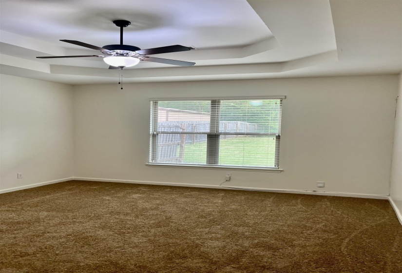 Carpeted spare room with baseboards, a ceiling fan, and a tray ceiling