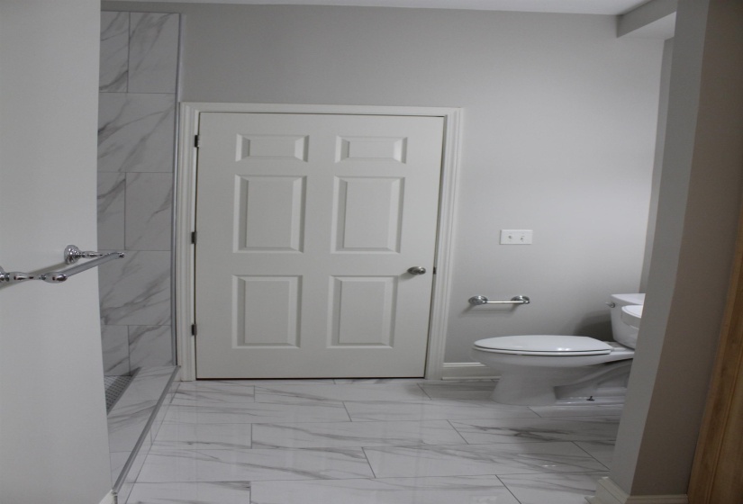 Full bath featuring marble finish floor, toilet, and a walk in shower