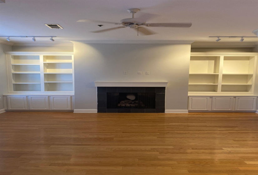 Unfurnished living room with crown molding, a tiled fireplace, a ceiling fan, visible vents, and light wood-style floors