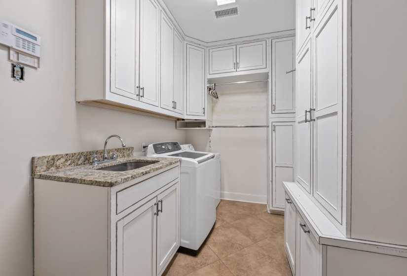 Laundry area with washing machine and dryer, tile floors, deep sink and custom cabinets