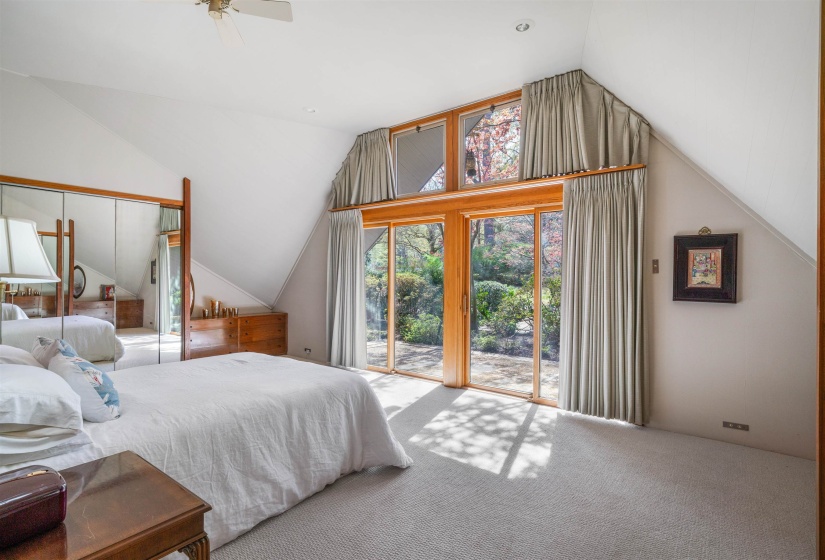 Primary bedroom with built-in dressers, private patio, vaulted ceiling