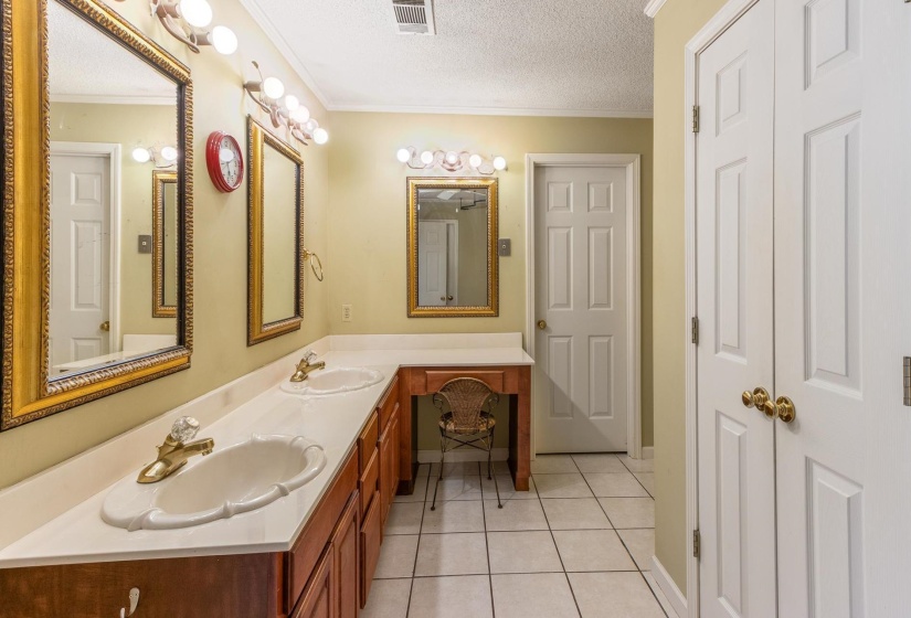 Full bathroom with light tile patterned floors, a textured ceiling, double vanity, and crown molding