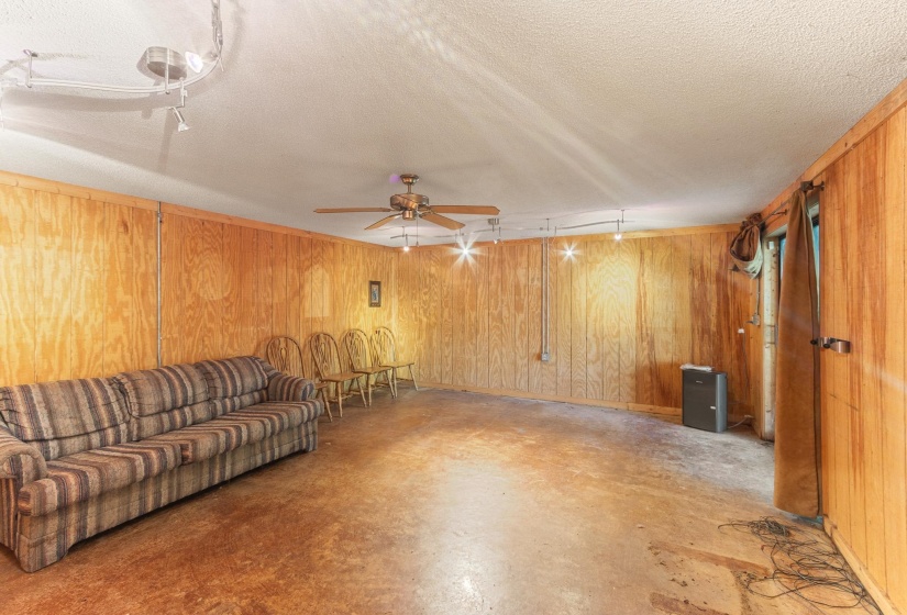 Unfurnished living room featuring concrete floors, a textured ceiling, wood walls, and a ceiling fan