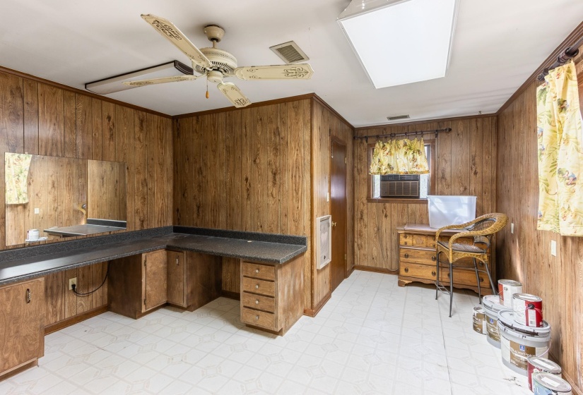Office area featuring light floors, wooden walls, a ceiling fan, heating unit, and built in desk