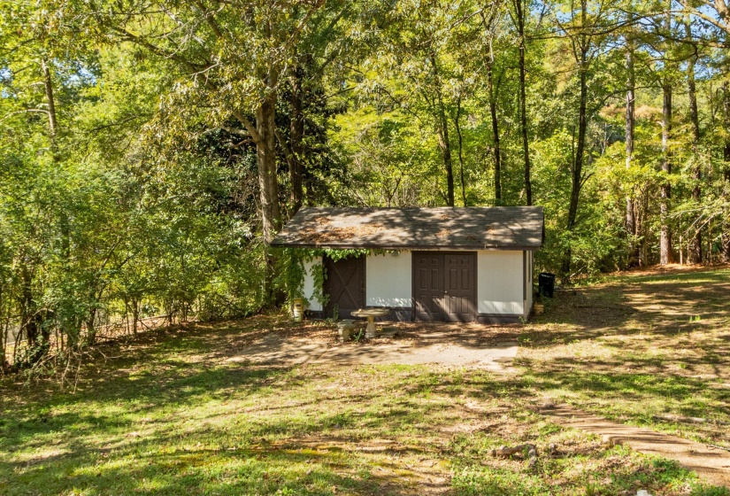 View of green lawn with a shed and a view of trees