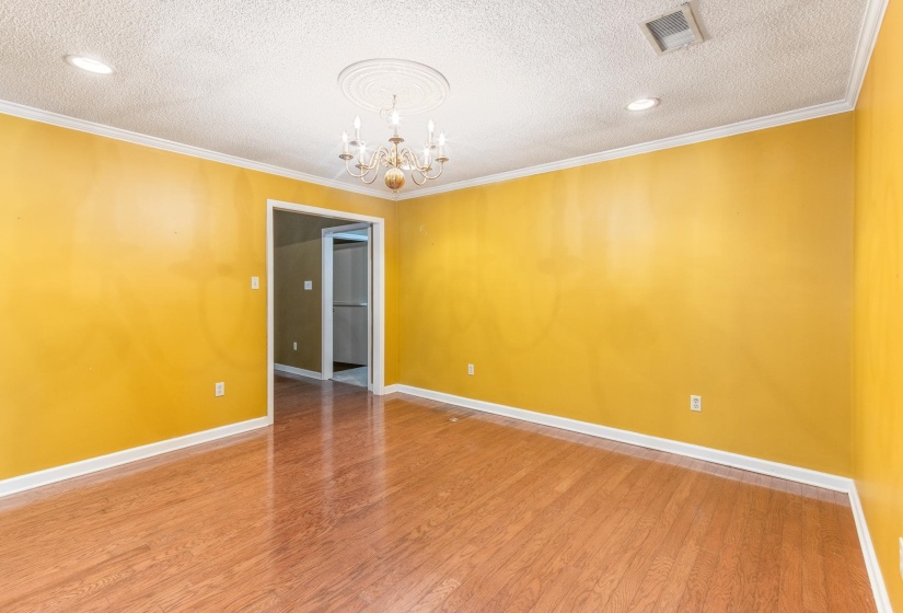 Unfurnished room featuring wood finished floors, a textured ceiling, crown molding, and a chandelier