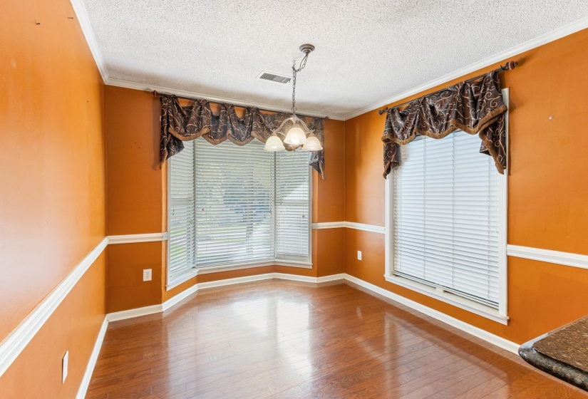 Unfurnished dining area with a textured ceiling, ornamental molding, a chandelier, and hardwood / wood-style flooring