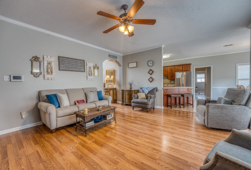 Living area with arched walkways, a textured ceiling, ceiling fan, and light wood-style flooring
