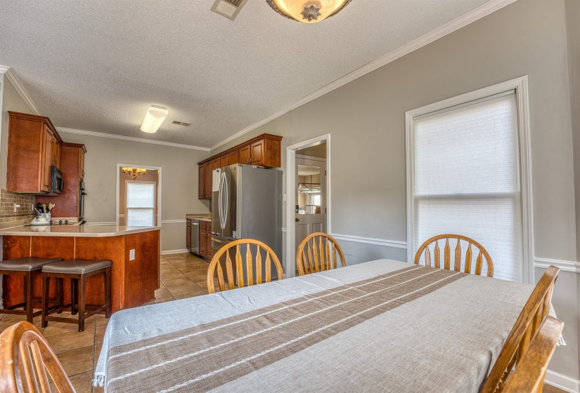 Dining room with a textured ceiling, visible vents, crown molding, baseboards, and light tile patterned floors