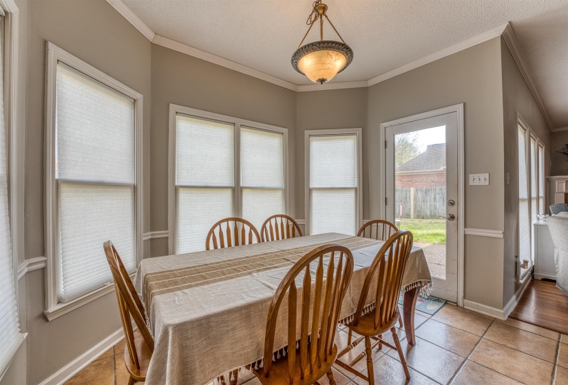 Dining room featuring light tile patterned flooring, baseboards, ornamental molding, and a textured ceiling