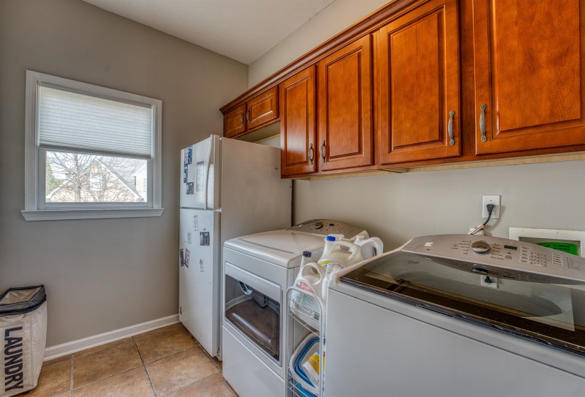 Washroom featuring independent washer and dryer, cabinet space, baseboards, and light tile patterned floors