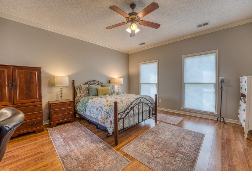 Bedroom featuring visible vents, crown molding, and light wood finished floors