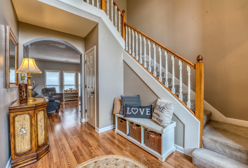 Staircase featuring arched walkways, baseboards, and wood finished floors
