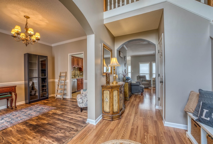 Corridor with arched walkways, crown molding, baseboards, and wood finished floors