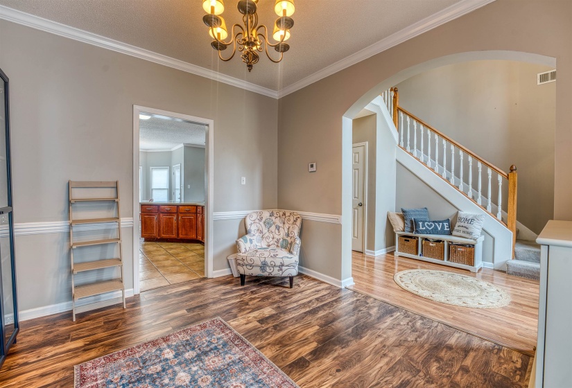 Living area with crown molding, stairs, arched walkways, visible vents, and wood finished floors