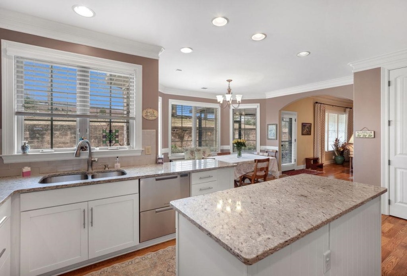 Kitchen featuring a notable chandelier, light stone counters, light wood-style floors, a sink, and arched walkways