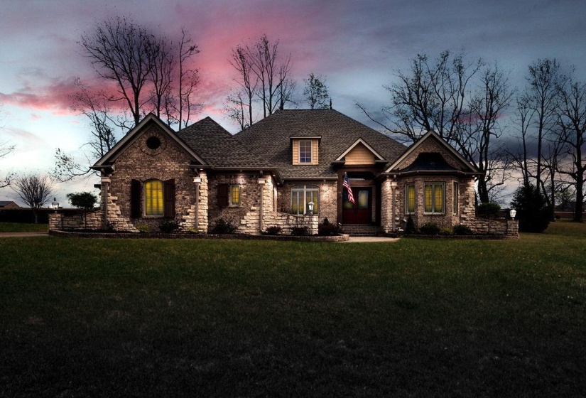 Craftsman-style house with stone siding, roof with shingles, and a yard