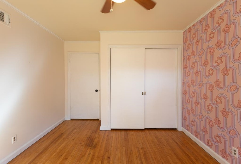 Unfurnished bedroom with a closet, light wood-type flooring, baseboards, visible vents, and ornamental molding